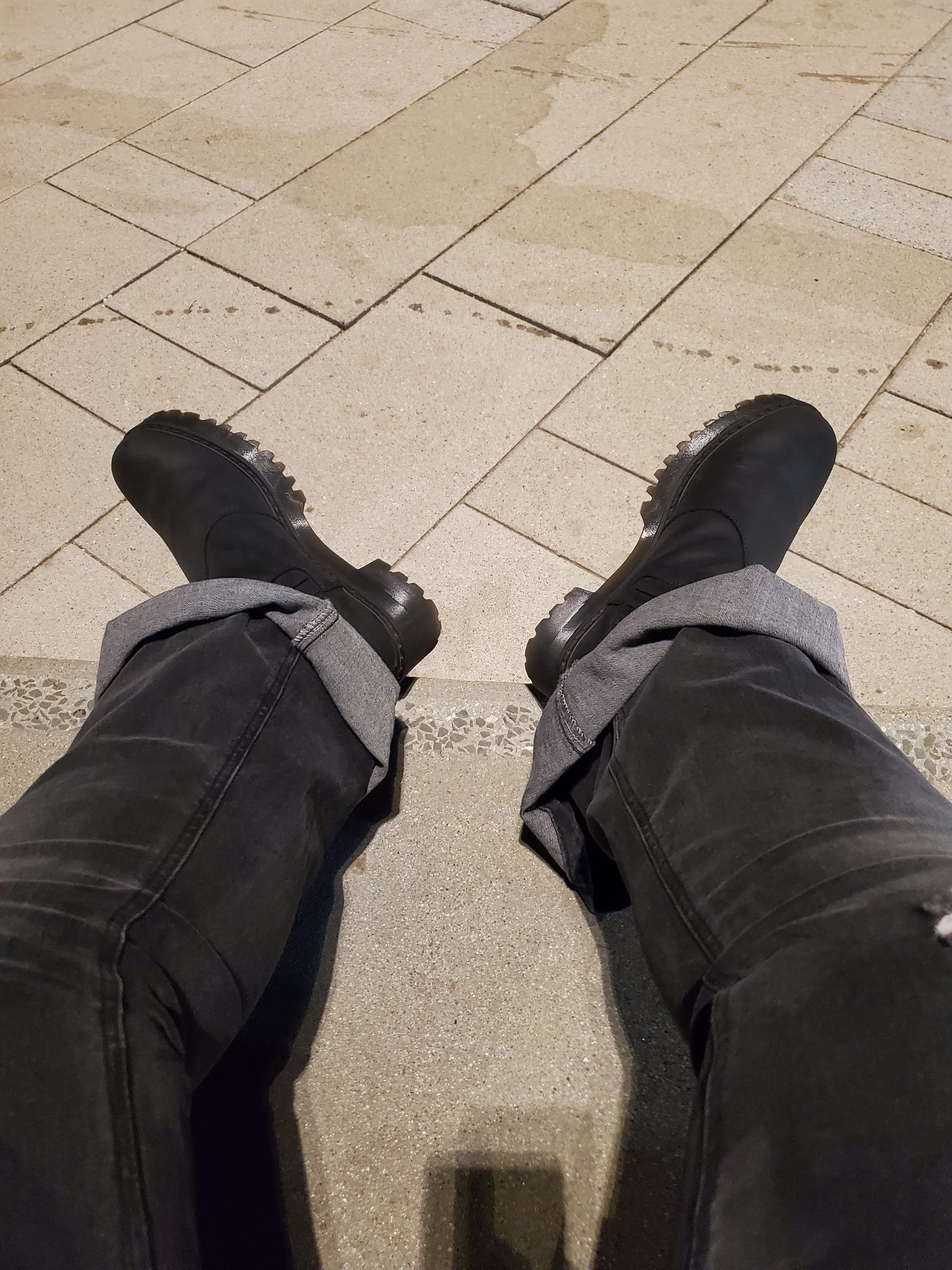 Photo of legs and booted feet resting on concrete step.