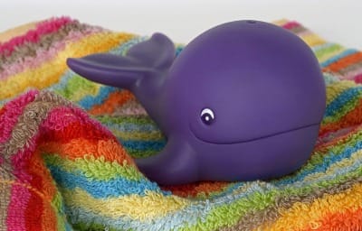 A purple whale toy sitting on a rainbow towel