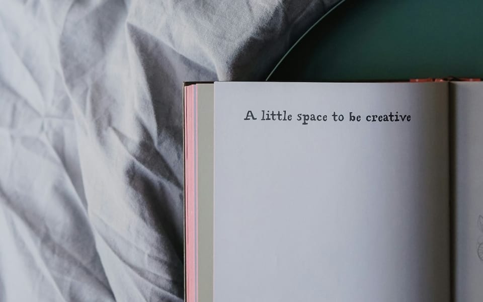 An open book with "A little space to be creative" written on the white page.