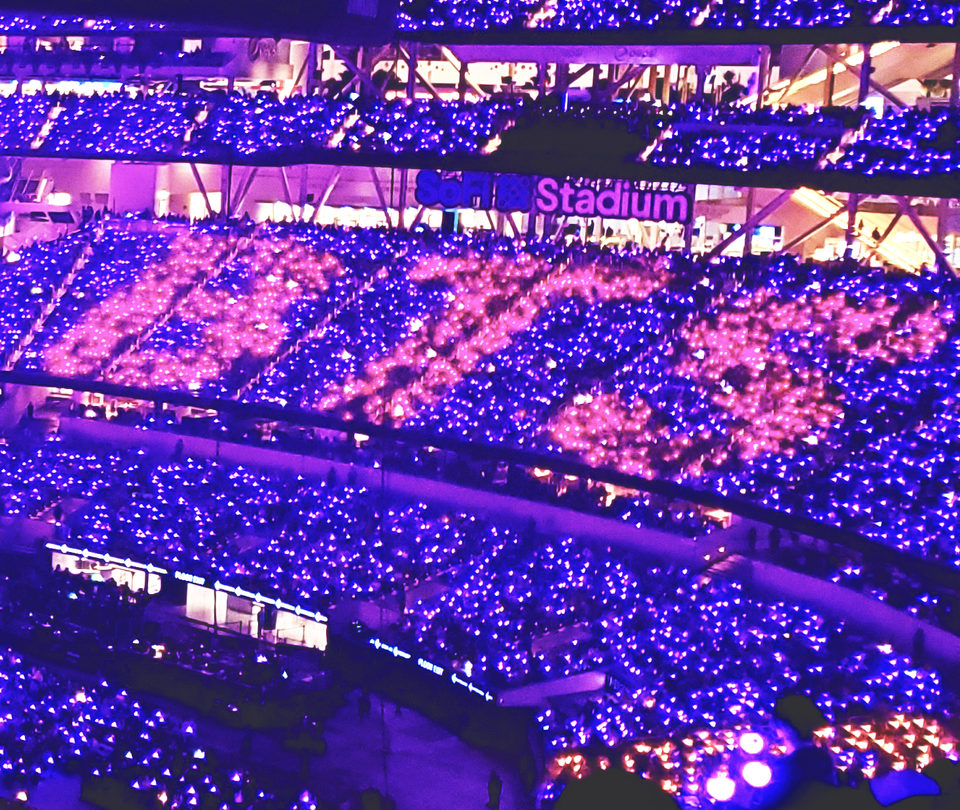 Sofi Stadium stands with purple and pink lights that spell BTS with the crowd.