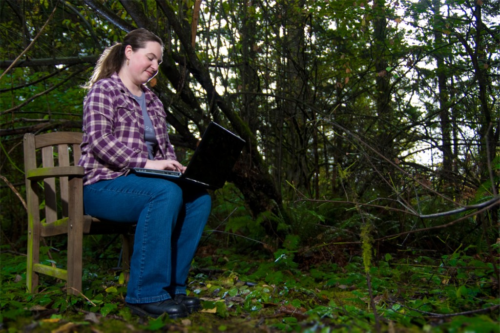 Kate with her laptop in the woods.